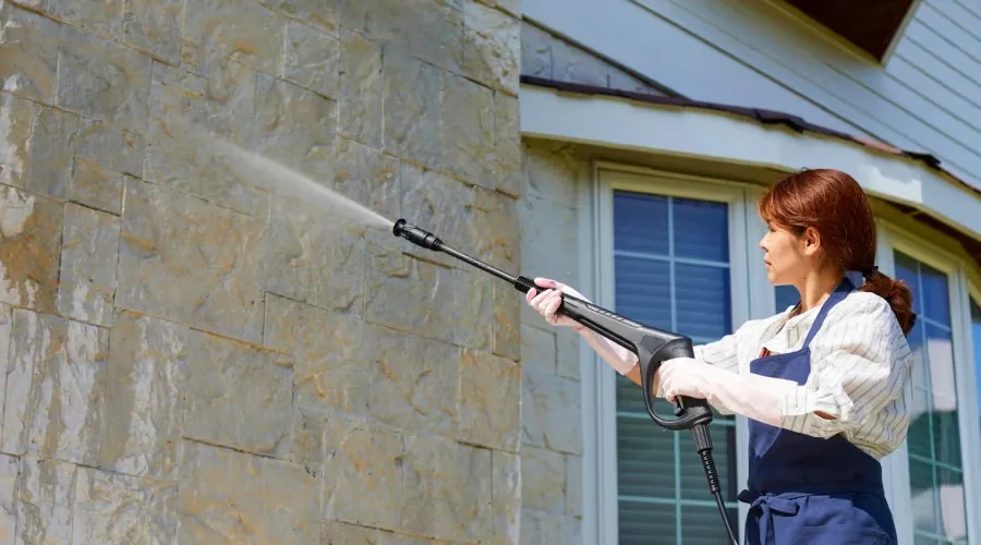 Stone veneer wall being cleaned with a pressure washer