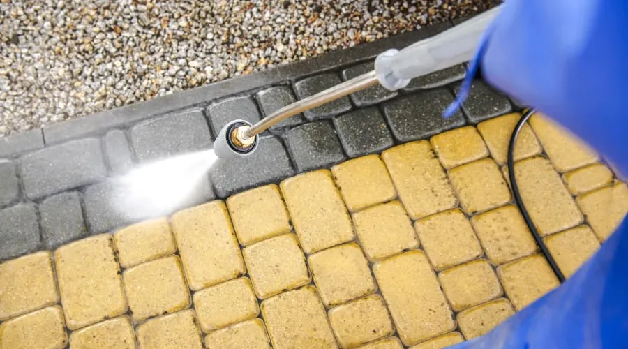 Overhead view of yellow pavers being cleaned with a surface spray